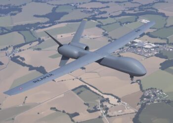 Avion militaire Reaper en vol au-dessus d'un paysage.