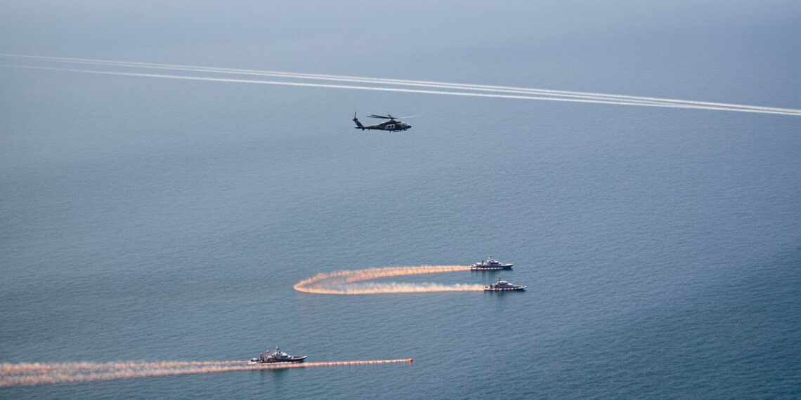 Hélicoptère militaire, deux patrouilleurs, bouées, fumée orange sur côte française.