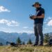 Aux premières lueurs du jour, un pilote de drone s’installe pour capturer des images aériennes, profitant de la douceur du lever de soleil.