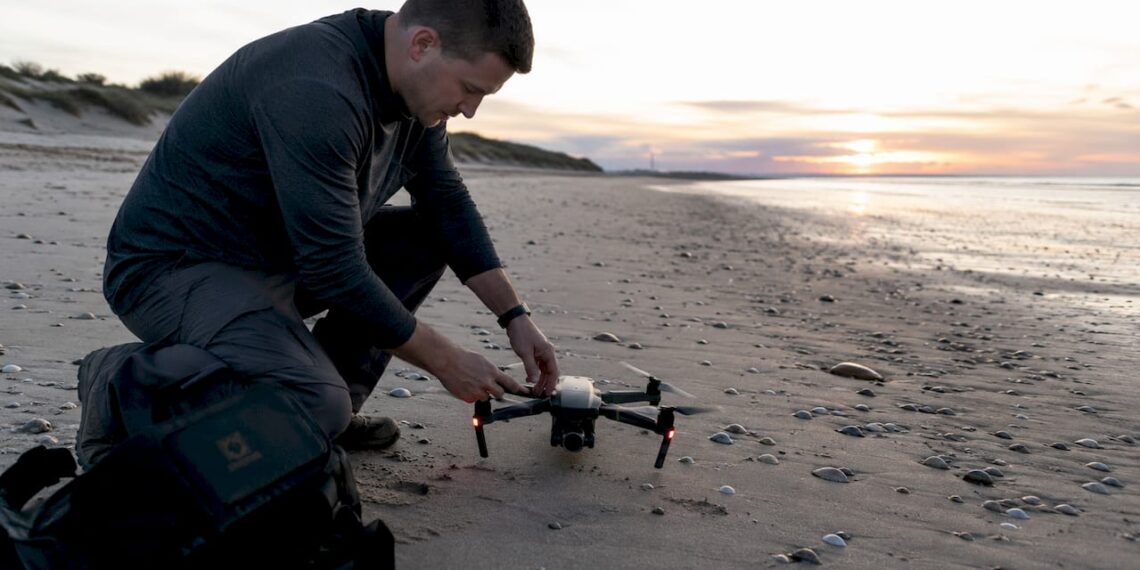 Un photographe installe son drone sur le toit d’un immeuble en ville.