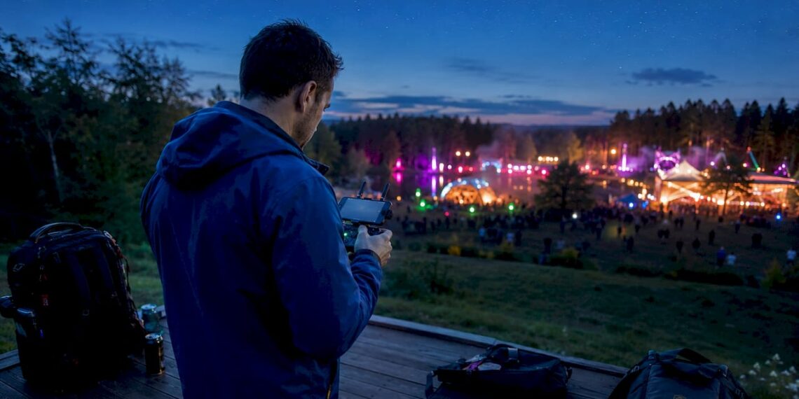 Un photographe pilote son drone au-dessus de la foule pendant une soirée de festival.