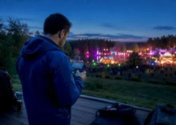 Un photographe pilote son drone au-dessus de la foule pendant une soirée de festival.