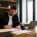 Des mains trient et classent des dossiers de contrats liés aux drones sur un bureau.