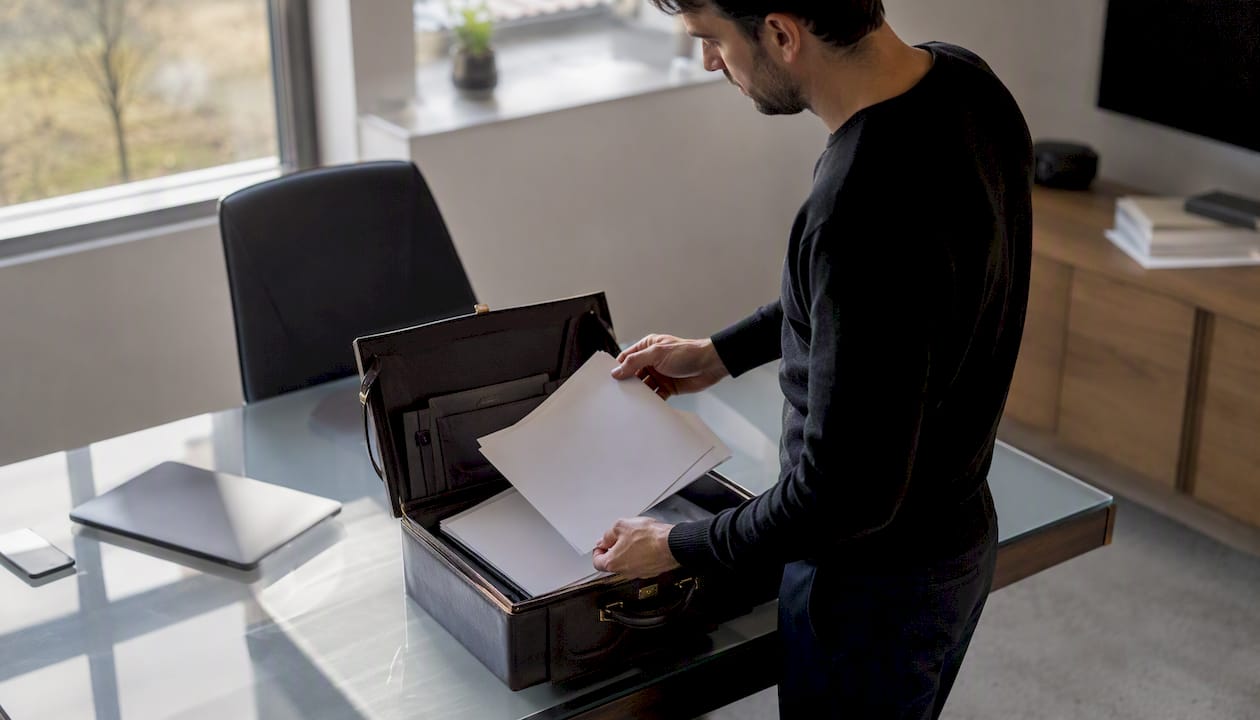 Des mains rangent des documents de conformité pour un drone dans une pochette.