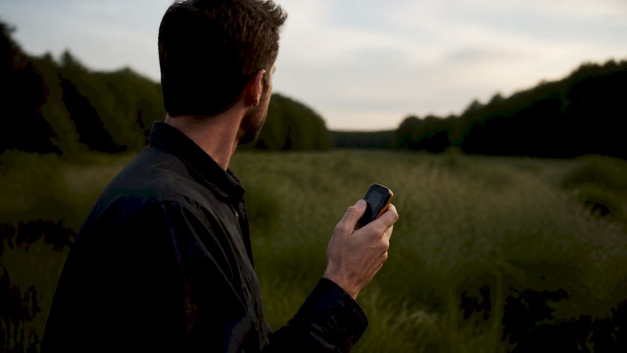 Une main tient un traceur GPS pour guider la recherche du drone.