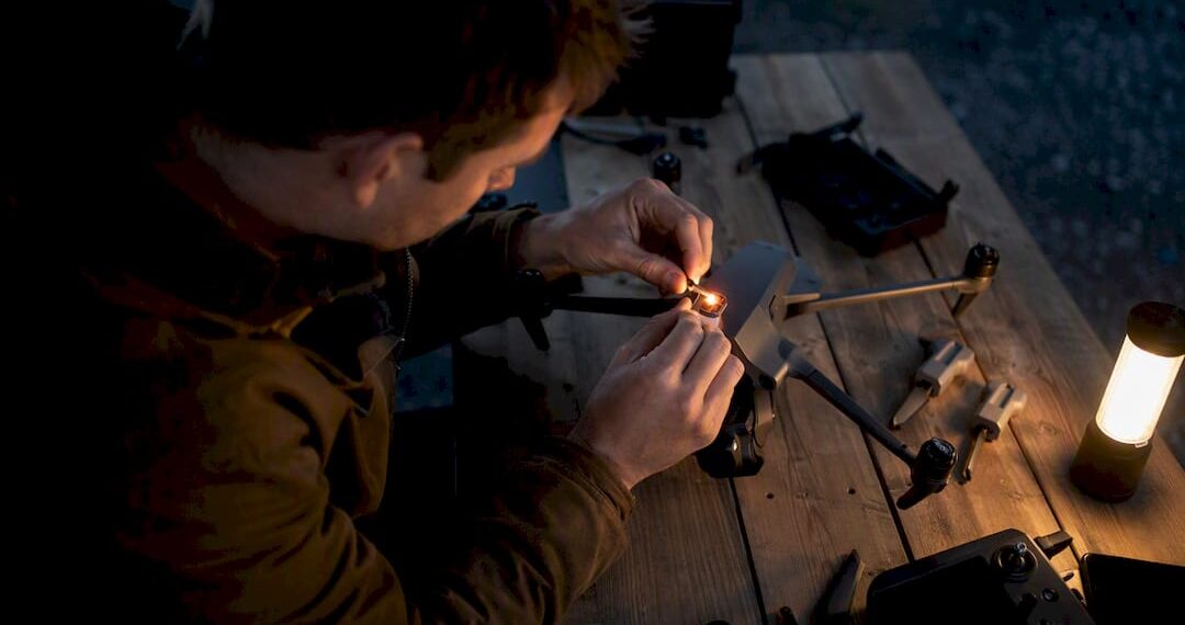 Pilote de drone fixant une lumière anti-collision au crépuscule