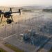 Drone professionnel avec caméra multicapteur survolant un poste électrique au lever du jour