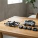 Petit drone caréné, télécommande à écran et trois batteries posés sur une table en bois