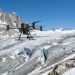 Drone équipé d’une antenne radar survolant un glacier alpin crevassé, deux alpinistes en veste orange au bord de la glace (illustration)