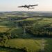 Drone à voilure fixe en vol au-dessus d’une ligne à haute tension traversant bocage et forêts