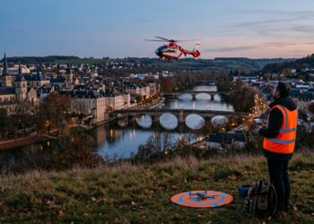 Télépilote au crépuscule observant un hélicoptère au-dessus d'une ville, illustration du salon European Rotors à Lyon