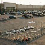 Drones de livraison sur leurs aires dans un enclos grillagé, sur le parking d’un hypermarché au soleil couchant