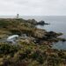 Drone en vol stationnaire au-dessus d’une côte rocheuse avec un phare